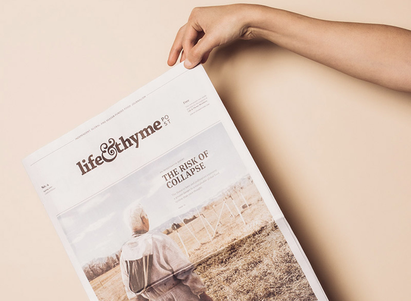 A person's hand dangling an issue of Life & Thyme newspaper