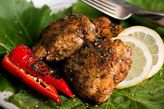 Grilled chicken thigh with za'atar laying on a bed of lettuce.