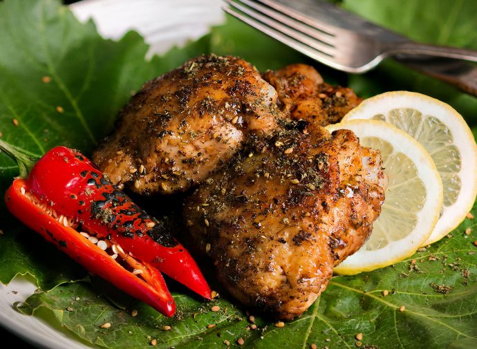 Grilled chicken thigh with za'atar laying on a bed of lettuce.